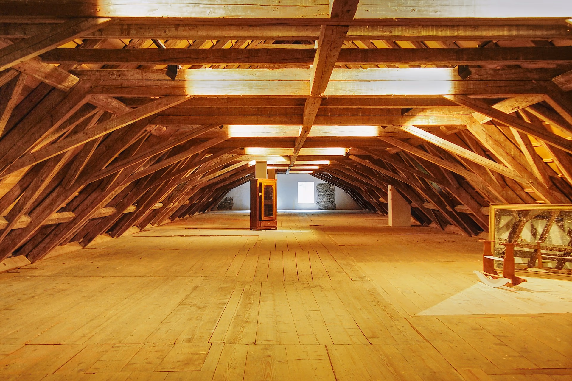 Intérieur ancien à poutres de bois et pierre, charpente massive baignée d'une lumière chaude, virage navy et noyer.