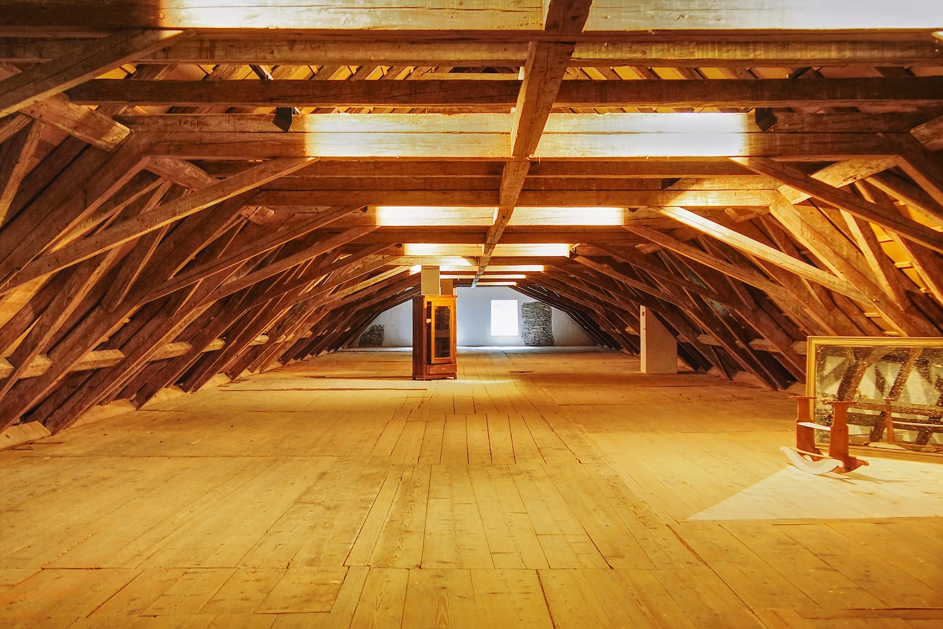 Intérieur ancien à poutres de bois et pierre, charpente massive baignée d'une lumière chaude, virage navy et noyer.