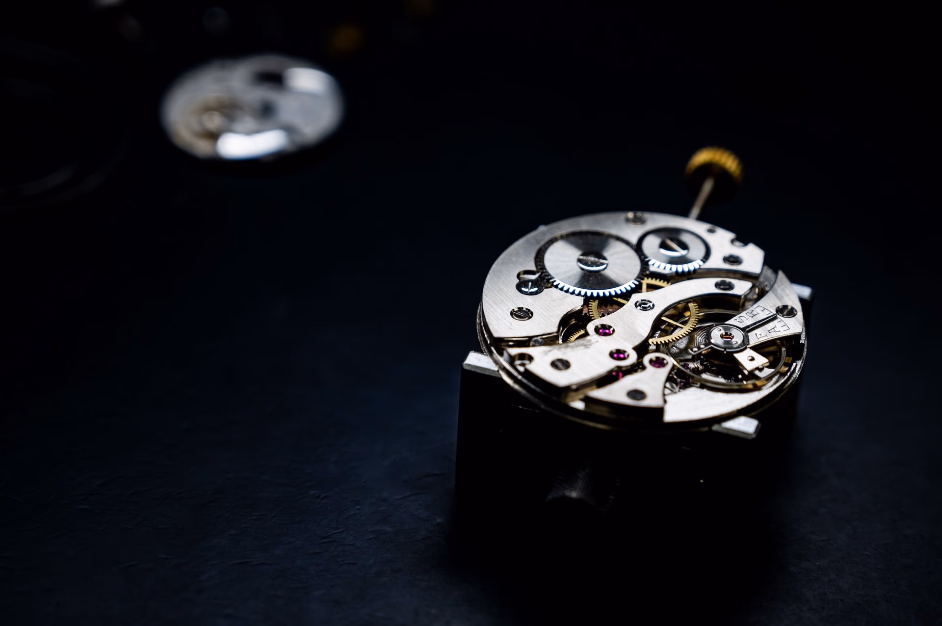 Mouvement de montre mécanique en gros plan, rouages d'acier et de laiton dans une lumière froide.